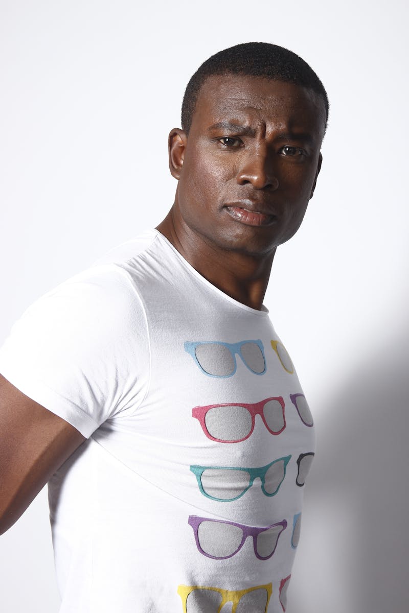 Serious portrait of a man wearing a graphic sunglasses t-shirt, indoors lighting.