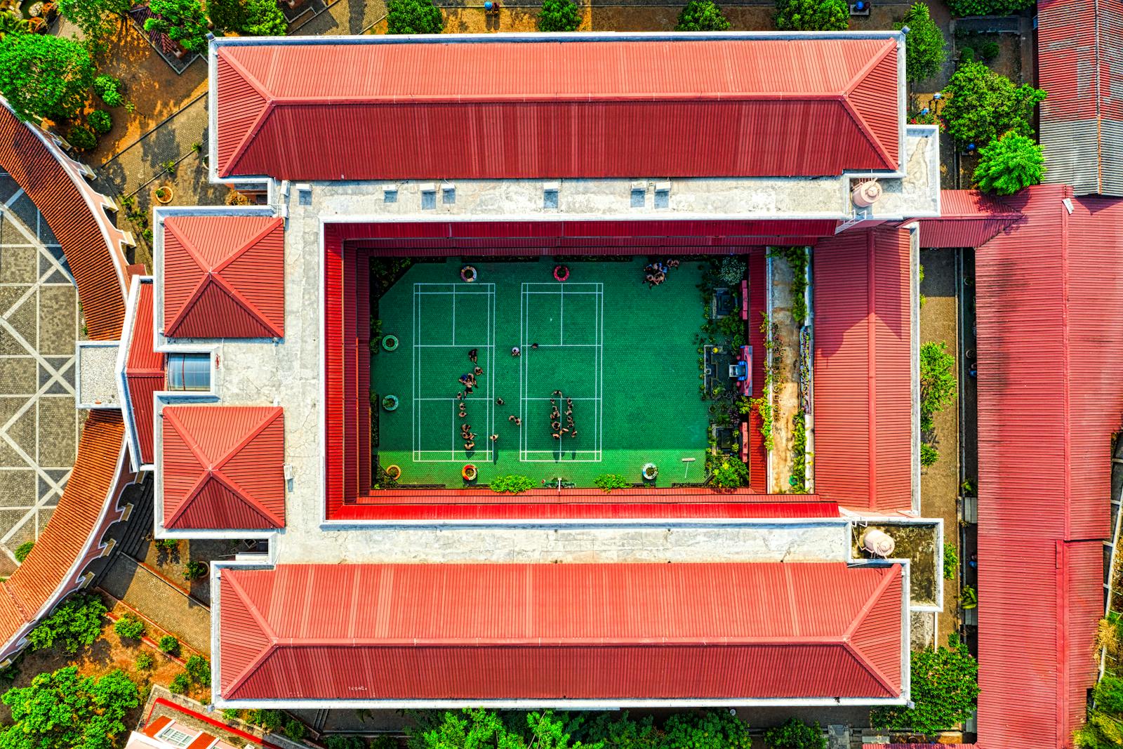 Drone view of a school courtyard with a green tennis court in Jakarta, Indonesia.